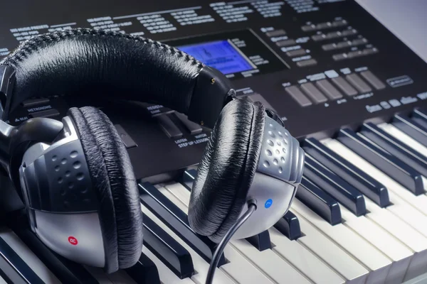 Headphones on top of a synthesizer buttons — Stock Photo, Image