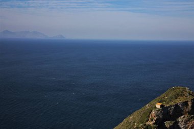 Kayadaki kırmızı ev okyanusla çevrili.