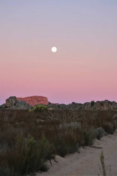 Güney Afrika 'da pembe gün batımı, kumlu yolun üzerinde büyük bir ay var.