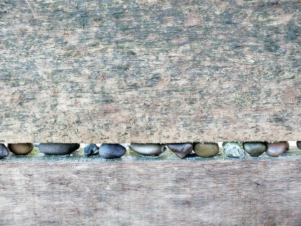 Textured background image, old pale wood with line of beach pebbles.