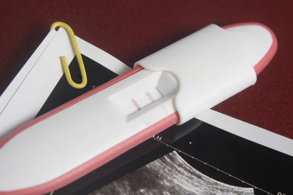 Hamilelik testi paketini koyu kırmızı arka plan — Stok fotoğraf