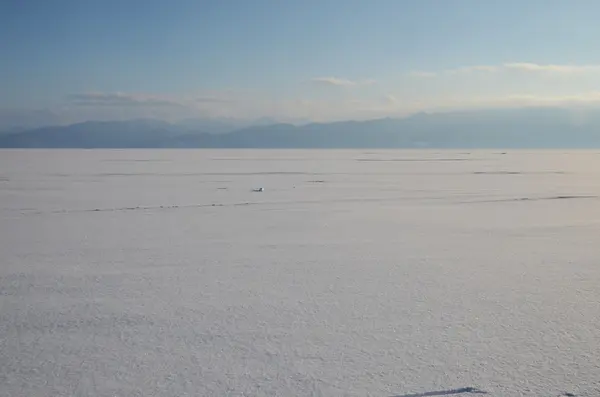 Glad oppervlak van besneeuwde bevroren Baikalmeer in avond — Stockfoto