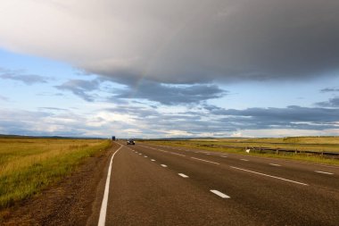 Tarlalar arasında yol alın. Yağmurdan sonra gökkuşağı. Rus manzarası