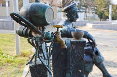 Telavi, Georgia - Feb, 28 2015:Mosquito-faucet with keg and rested man in cap - original bench-sculpture in Telavi. Georgia