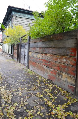 Kaldırım düşen sarı yapraklar ve eski ahşap eski püskü çit ile. Irkutsk street, Rusya Federasyonu