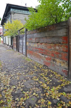 Kaldırım düşen sarı yapraklar ve eski ahşap eski püskü çit ile. Irkutsk street, Rusya Federasyonu