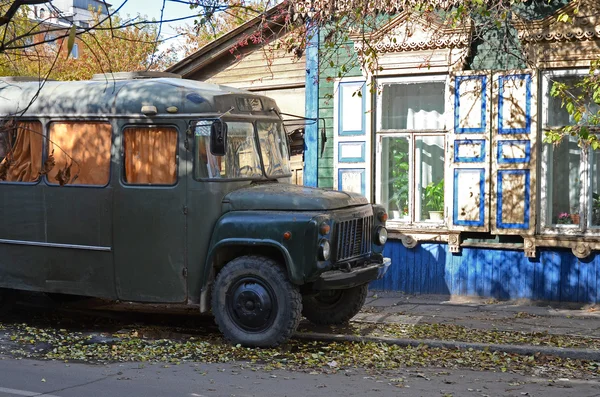 Alter sowjetischer Bus kavz 685 auf der Straße neben dem Holzhaus mit Schnitzereien. irkutsk, russisch — Stockfoto