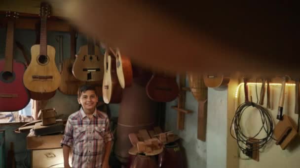 1-pojke i luta Maker Shop titta på klassiska gitarrer — Stockvideo