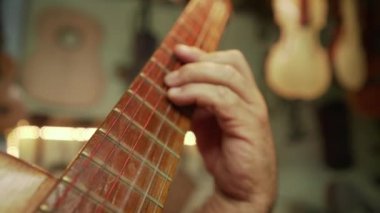 12-yaşlı adam UD yapımcısı dükkanda klasik gitar çalmak