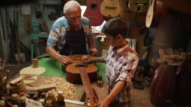 5-luit Maker opa onderwijzen van jongen kleinzoon Tuning gitaar — Stockvideo