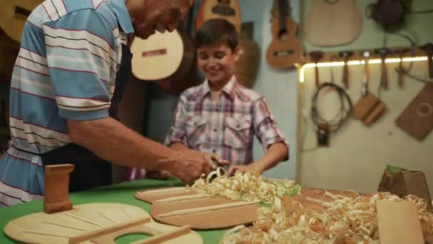 8-старший чоловік лютні Maker викладання хлопчик Chiseling деревини — стокове відео