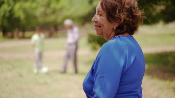 Счастливая старшая бабушка играет в футбол с семьей — стоковое видео
