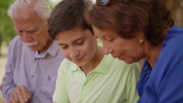 Niño ayudando a los abuelos a ir a Internet por teléfono — Vídeo de stock