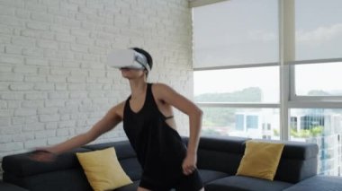 Spor aktiviteleri yapan genç bir kadın evde spor yapmak için sanal gerçeklik kulaklığı takıyor. Eğlence ve eğlence için sanal gerçeklik maskesiyle çalışan bir kız. İnsanlar sağlıklı bir yaşam için antrenman yapıyor. Yavaş çekim