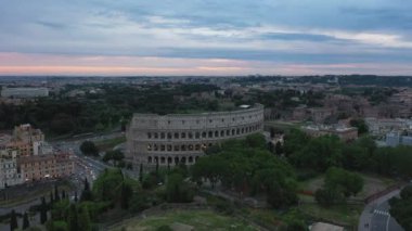 Colosseo 'nun havadan görünüşü, Roma, İtalya' nın ünlü simgesi. Roma 'daki Flavian Amfitiyatrosu gökyüzünde uçan insansız hava aracından görüldü. Antik Roma binası ve alacakaranlıkta trafiği olan İtalyan şehrinin şehir manzarası
