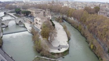 Tiber Adası 'nın havadan görünüşü, Roma, İtalya' nın turistik yerleri. Roma 'da İsola Tiberina, İtalya' da Tevere nehri ile gökyüzünde uçan insansız hava aracından görüldü. Eski binalar, İtalyan şehrinin kentsel manzarası