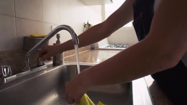 Жена делает уборку уборка салфетки под тонущей водой кухни — стоковое видео