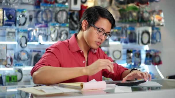 Chinese Man aan het werk In computerwinkel facturen controleren — Stockvideo