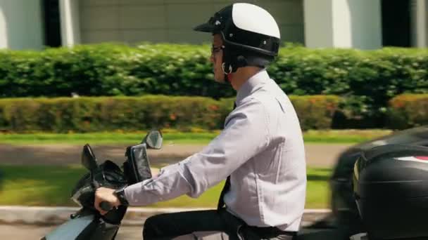 Commuter chino del hombre de negocios que monta la motocicleta de la vespa en ciudad — Vídeo de stock