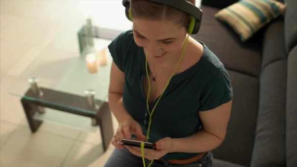 Frau hört Musik-Podcast am Telefon mit Kopfhörern — Stockvideo