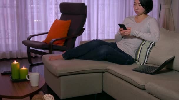Японка на диване с смартфоном для интернета — стоковое видео