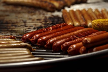 Izgara sosis. Barbekü sosis. BBC partisiyle tanışın. Kızarmış domuz eti ve bira ızgara sosisler ateşte cızırdıyor. Sıcak Alman gurme yemeği yuvarlak ızgarada işlendi. Yağlı ve baharatlı sosisli sandviç.