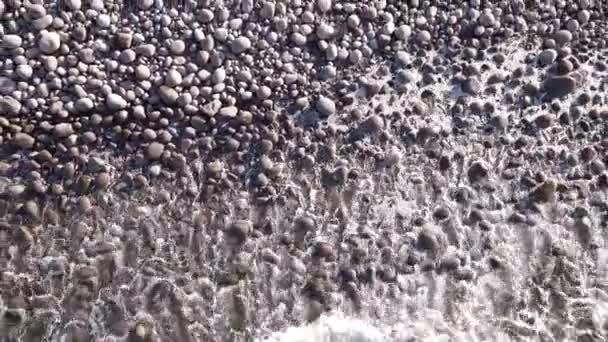 Zimní vzdušný let nad vlnami valícími se na uměleckém pobřeží oceánu s kulatými kameny, oceánské vlny v bouři — Stock video