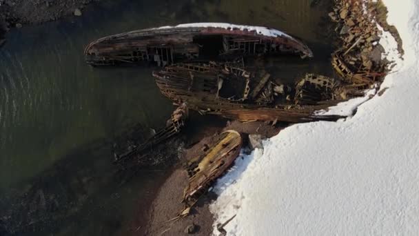 Luftaufnahme alter zerstörter Fischerboote, die in der verschneiten Wintersaison an der Küste ertrunken sind. Verfilmung. Luftaufnahme des zerstörten Bootes im kalten Wasser nahe der verschneiten Sandküste in Teriberka, Russland — Stockvideo