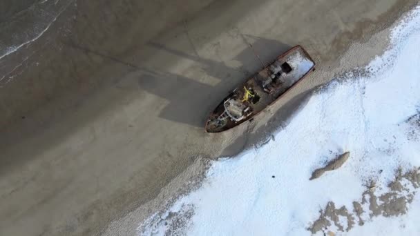 Luftaufnahme alter zerstörter Fischerboote, die in der verschneiten Wintersaison an der Küste ertrunken sind. Verfilmung. Luftaufnahme des zerstörten Bootes im kalten Wasser nahe der verschneiten Sandküste in Teriberka, Russland — Stockvideo