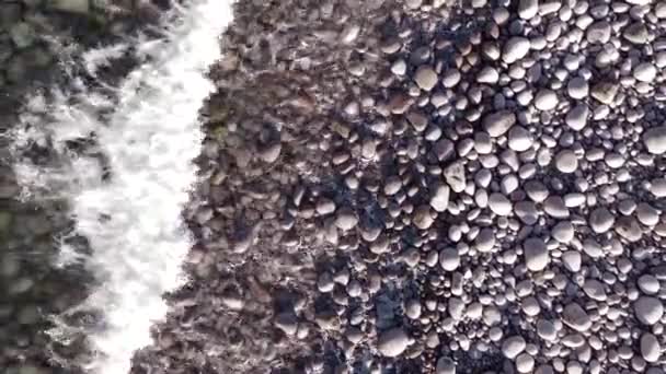 Vuelo aéreo de invierno superior sobre las olas rodando en la orilla ártica del océano con piedras redondas, olas del océano en la tormenta — Vídeos de Stock