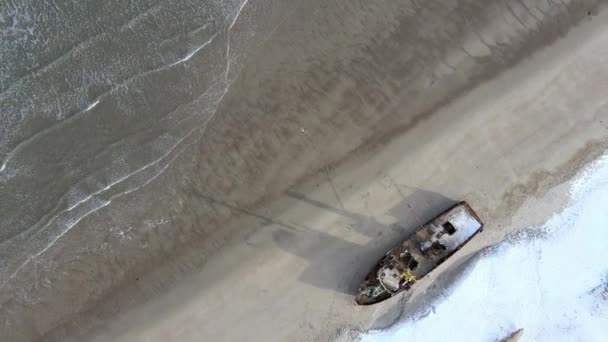 在多雪的冬季，空中俯瞰着失事的旧渔船在海滨溺亡。镜头。俄罗斯Teriberka雪地沙滩海岸附近冷水中被毁船只的空中照片 — 图库视频影像