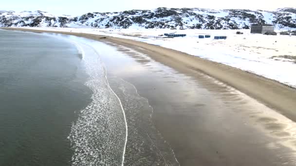 Karlı kış mevsiminde deniz kıyısında boğulan eski batık balıkçı gemilerinin hava manzarası. Görüntü. Rusya 'nın Teriberka kentindeki karlı sahil kıyısındaki soğuk sulardaki harabe teknenin hava görüntüsü. — Stok video