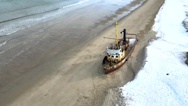 Karlı kış mevsiminde deniz kıyısında boğulan eski batık balıkçı gemilerinin hava manzarası. Görüntü. Rusya 'nın Teriberka kentindeki karlı sahil kıyısındaki soğuk sulardaki harabe teknenin hava görüntüsü. — Stok video
