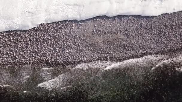 Vinter antenn flygning topp över vågor rullande på arktisk ocean strand med runda stenar, havsvågor vid storm — Stockvideo