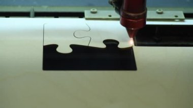 Oyuncak fabrikasında otomatik tahta yapboz üretimi. Lazer ışınıyla kontrplak keserken çekilmiş 4K makro görüntü. Tahta oyuncaklar tasarım konsepti