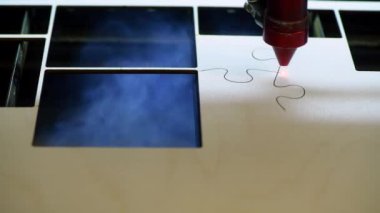 Oyuncak fabrikasında otomatik tahta yapboz üretimi. Lazer ışınıyla kontrplak keserken çekilmiş 4K makro görüntü. Tahta oyuncaklar tasarım konsepti