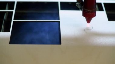 Oyuncak fabrikasında otomatik tahta yapboz üretimi. Lazer ışınıyla kontrplak keserken çekilmiş 4K makro görüntü. Tahta oyuncaklar tasarım konsepti