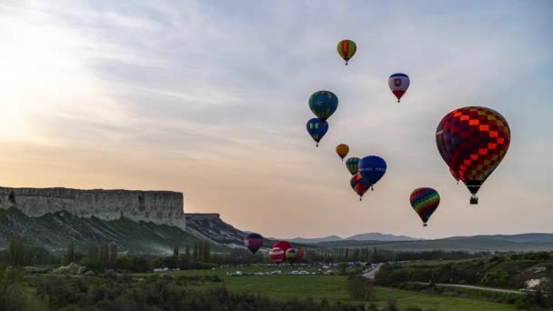 Gyönyörű sziklás táj Krím színes hőlégballonok ballonok repülő naplemente, 4k HDR Time Lapse felvételek — Stock videók