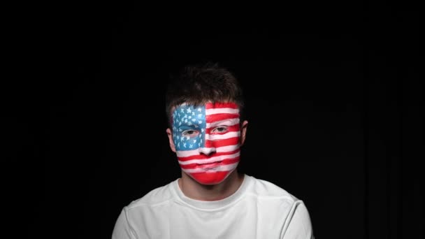 Happy fan rejoices victory of his favorite team of USA. Young man with face painted in national colors of United states of america. Portrait of a happy man supports his national team — Stock Video