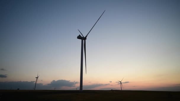 Yel değirmeni çiftliğinin manzarası, günbatımında enerji üretimi için rüzgar jeneratörleri. Rüzgar güç türbinleri temiz yenilenebilir enerji üretiyor — Stok video