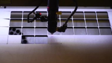 Oyuncak fabrikasında otomatik tahta yapboz üretimi. Lazer ışınıyla kontrplak keserken çekilmiş 4K makro görüntü. Tahta oyuncaklar tasarım konsepti
