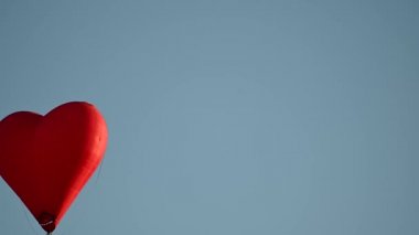 Gün batımında mavi gökyüzünde yavaş çekimde uçan renkli sıcak hava şekilli balon Sevgililer Günü konseptin kutlu olsun. 4k HDR Yüksek kalite görüntü
