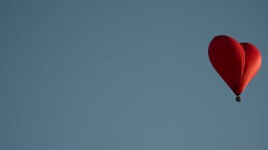 Gün batımında mavi gökyüzünde yavaş çekimde uçan renkli sıcak hava şekilli balon Sevgililer Günü konseptin kutlu olsun. 4k HDR Yüksek kalite görüntü