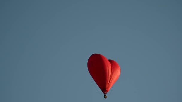 Colorido globo en forma de corazón de aire caliente que vuela al atardecer sobre el cielo azul en cámara lenta, concepto del Día de San Valentín feliz. 4k HDR Imágenes de alta calidad — Vídeo de stock