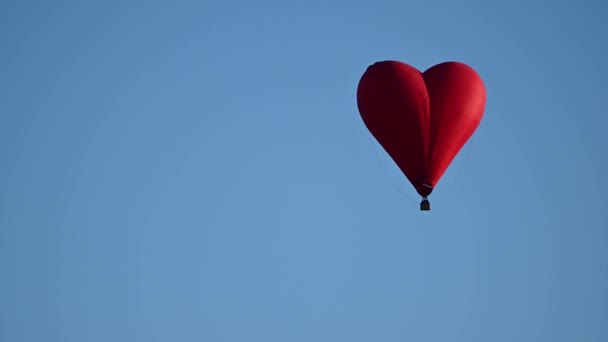 Colorido globo en forma de corazón de aire caliente que vuela al atardecer sobre el cielo azul en cámara lenta, concepto del Día de San Valentín feliz. 4k HDR Imágenes de alta calidad — Vídeos de Stock