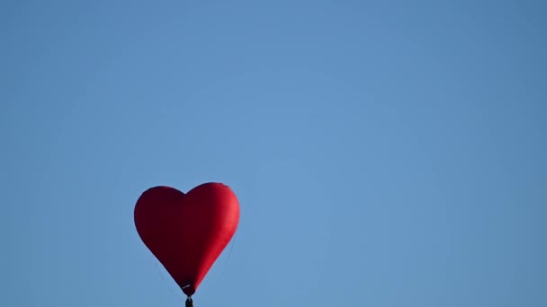 Kolorowe gorące powietrze w kształcie serca balon latający na zachodzie słońca nad błękitnym niebem w zwolnionym tempie, koncepcja Happy Valentines Day. 4k HDR Wysokiej jakości nagrania — Wideo stockowe