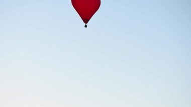 Gün batımında mavi gökyüzünde yavaş çekimde uçan renkli sıcak hava şekilli balon Sevgililer Günü konseptin kutlu olsun. 4k HDR Yüksek kalite görüntü