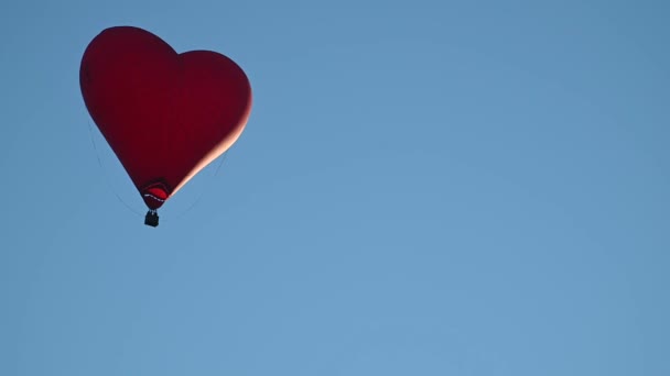 Barevný horkovzdušný balón ve tvaru srdce letící při západu slunce nad modrou oblohou ve zpomaleném filmu, koncept Šťastného Valentýna. 4k HDR Kvalitní záběry — Stock video