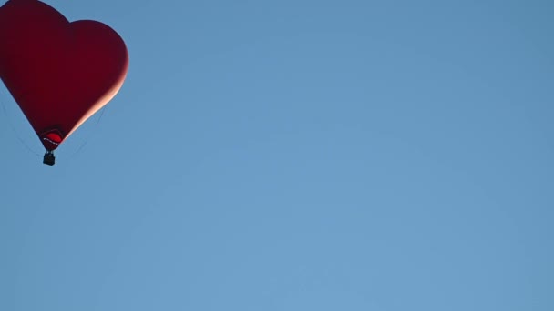 Colorido globo en forma de corazón de aire caliente que vuela al atardecer sobre el cielo azul en cámara lenta, concepto del Día de San Valentín feliz. 4k HDR Imágenes de alta calidad — Vídeos de Stock