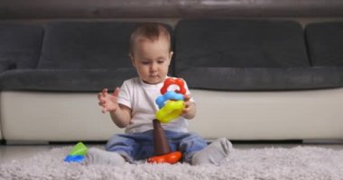 Evinde renkli piramit oyuncağıyla oynayan sevimli bir erkek bebek.